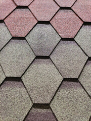 The roof is covered with hexagonal asphalt soft tiles. Abstract geometric background on the theme of modern architecture or construction industry.