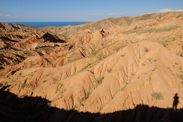 Shadow of photographer in the Skazka fairytale canyon. Lake Issyk-Kul in the background. Tosor,...