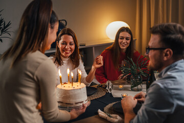 Birthday girl brings a cake in front of her friends
