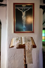 holy bible on a pedestal next to a wall with a picture of Jesus Christ crucified. biblical image....