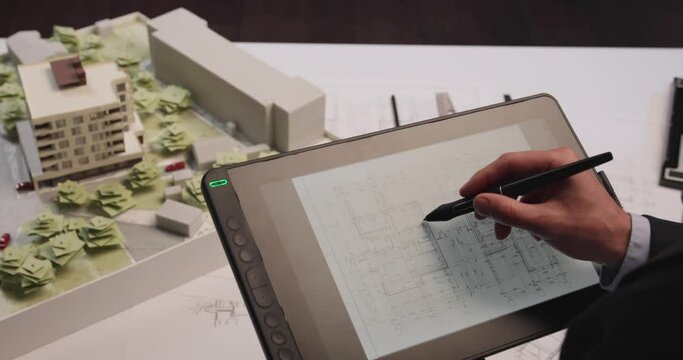 Man architect uses tablet computer and draws project of building