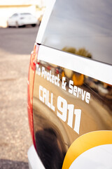 Obraz premium Vertical image of back end of a police car vehicle reading Protect and serve call 911