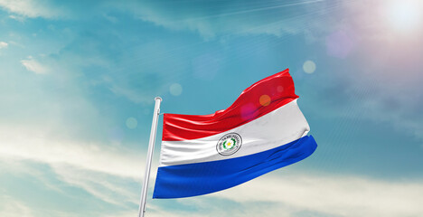 Waving Flag of Paraguay in Blue Sky. The symbol of the state on wavy cotton fabric.
