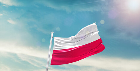 Waving Flag of Poland in Blue Sky. The symbol of the state on wavy cotton fabric.