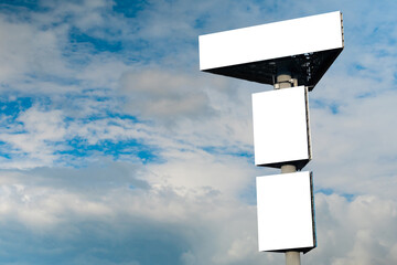 Mock up - three blank white billboards or large advertising displays against blue sky with white...