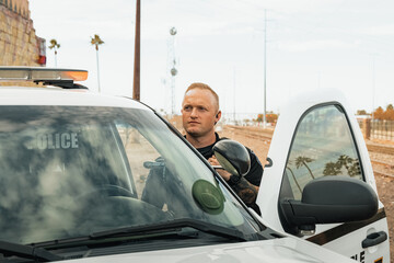 Horizontal image of white male caucasian police officer standing in the door opening of his trooper...