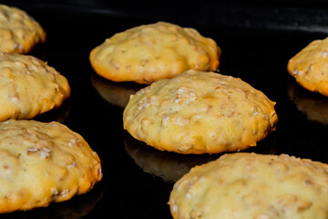 Many baked homemade crunchy oatmeal cookies on metal sheet in oven - close up. Dessert, cookery,...