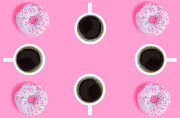 Donut with pink glaze and coffee cup on the pink background. Copy space. Top view.