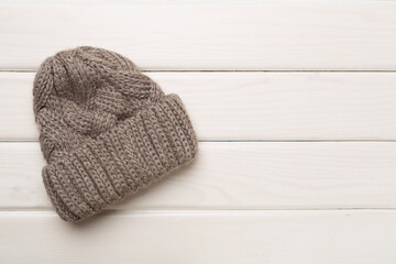 Grey winter hat on wooden background. Top view