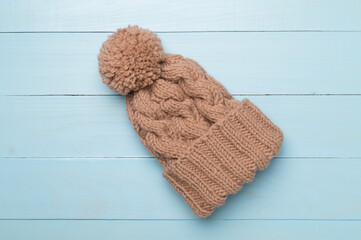 Brown winter hat on wooden background. Top view