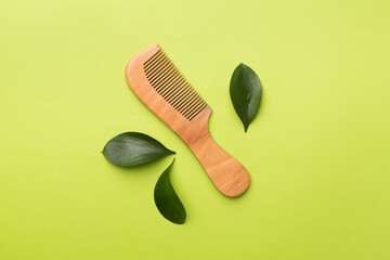 Hair comb with green leaves color on background. Top view