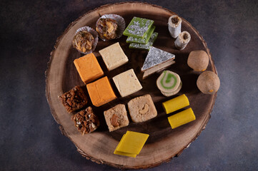 Assorted Indian sweets for Indian festivals arranged in a wood board top view.  Festival sweets or Indian Mithai made with milk, cashews. 