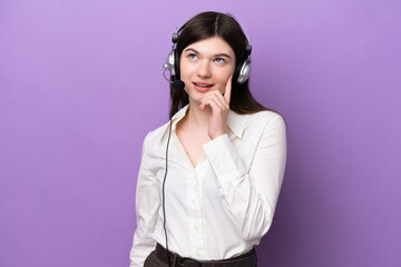 Telemarketer Russian woman working with a headset isolated on purple background thinking an idea while looking up