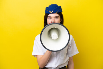 Airplane stewardess Russian woman isolated on yellow background shouting through a megaphone