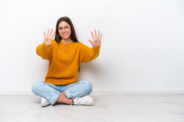 Young girl sitting on the floor isolated on white background counting nine with fingers