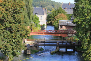 the river durdent in cany barville in seine maritime in normandy with a bridge and a weir and green trees and houses in summer - obrazy, fototapety, plakaty