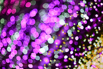 Blurred bokeh of purple-yellow lights of Christmas garlands