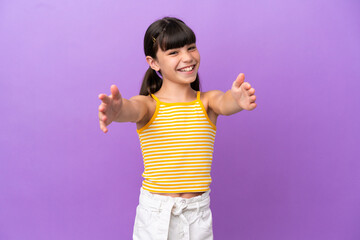 Little caucasian kid isolated on purple background presenting and inviting to come with hand