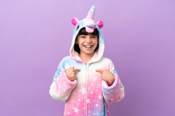 Little kid wearing a unicorn pajama isolated on purple background with surprise facial expression