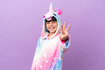 Little kid wearing a unicorn pajama isolated on purple background happy and counting three with fingers