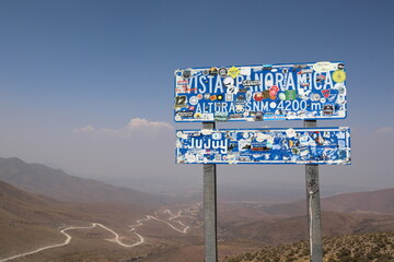 Road sign full of stickers of travelers showing 4200 meters high view near Salta, Argentina