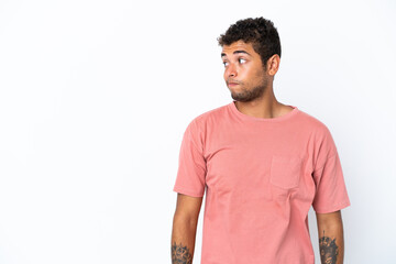 Young handsome Brazilian man isolated on white background making doubts gesture looking side