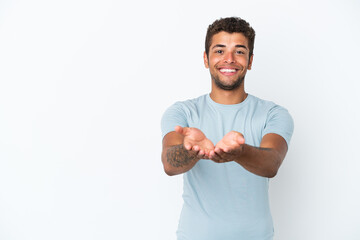 Young handsome Brazilian man isolated on white background holding copyspace imaginary on the palm...