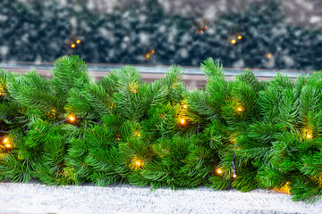Decorated Christmas tree branches with luminous garlands during a snowfall.