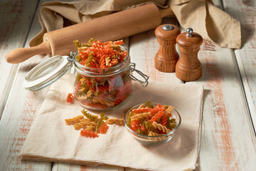 Tricolor raw fusilli pasta on a rustic background