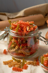 Tricolor raw fusilli pasta on a rustic background