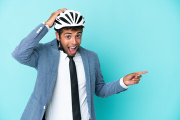 Young business Brazilian man with bike helmet isolated on blue background surprised and pointing finger to the side