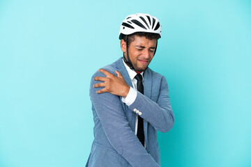 Young business Brazilian man with bike helmet isolated on blue background suffering from pain in shoulder for having made an effort