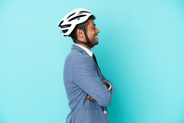 Young business Brazilian man with bike helmet isolated on blue background in lateral position