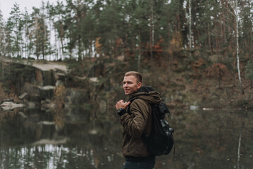 man traveler stands with a backpack on the background of a quarry