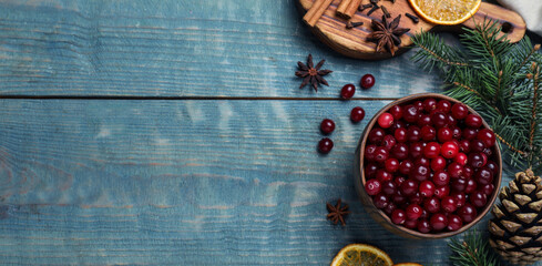 Flat lay composition with fresh ripe cranberries on blue wooden table, space for text. Banner design