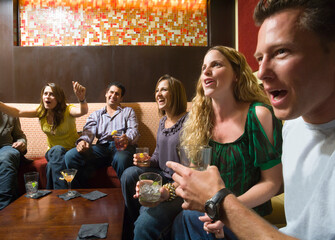 Men and women socializing in a bar in the city. Group of festive, smiling people celebrating with drinks. California USA