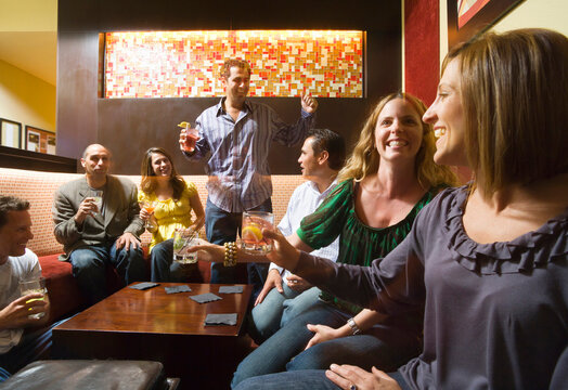 Men and women socializing in a bar in the city. Group of festive, smiling people celebrating with drinks. California USA