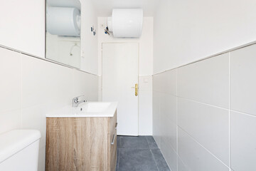 Small bathroom with mirror-door cabinet, light-wood framed mirror, and porcelain sink