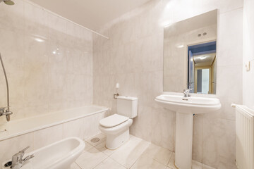 Bathroom with white porcelain toilets, rectangular frameless mirror and white tiles