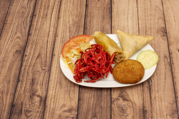 An Indian starter plate with samosas, cheese rolls, onion and tomato bashi