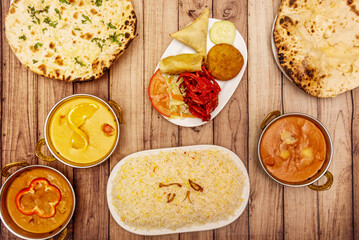 Set of typical Indian food dishes with cheese garlic naan, biryani rice, different sweet and spicy curries and starter dish