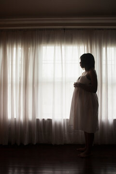 Silhouette of Pregnant Woman Looking out Window
