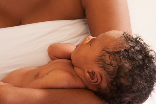 Sleeping Newborn Baby Cradled in Mother's Arms