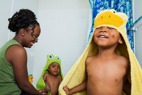 Mother Helping Boys put on Hooded Towels after Bath