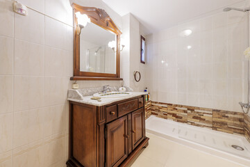 Bathroom with rustic-style wooden furniture and a mirror with a wooden frame to match the sconces, a gray marble countertop and a shower cabin with a glass screen