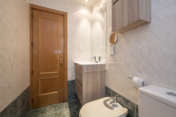 Bathroom with new wooden furniture, green tiles on the floor and pine wood door