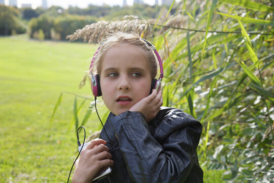 Young Girl Sitting Outside Listening to Music