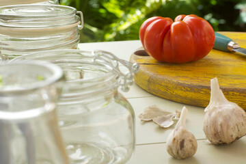 Tomato on Cutting Board with Garlic and Glass Jars