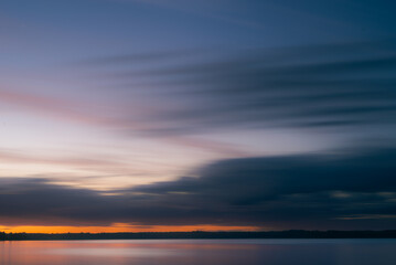 Fototapeta na wymiar Cloudy dawn over lake in summer