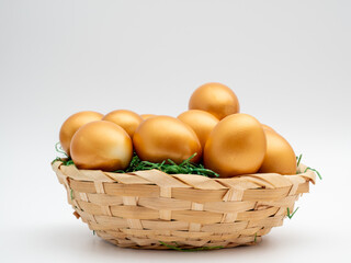 Golden eggs in a wicker basket on a white background. Golden chicken eggs.